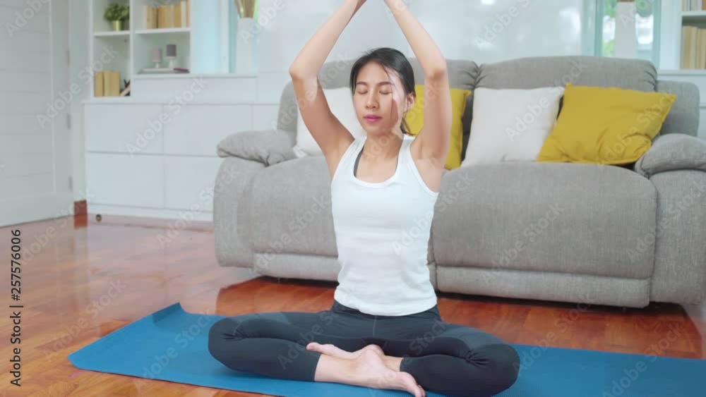 Young Asian woman practicing yoga in living room. Attractive beautiful female working out for healthy at home. Lifestyle woman exercise concept. Young Asian woman practicing yoga in living room. Attractive beautiful female working out for healthy at home. Lifestyle woman exercise concept.