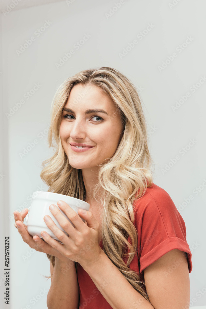 Blonde drinking coffee, tea or soup from a white cup Blonde drinking coffee, tea or soup from a white cup