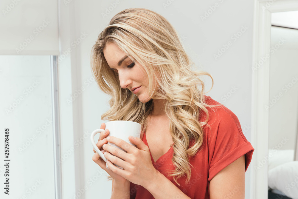 Blonde drinking coffee, tea or soup from a white cup Blonde drinking coffee, tea or soup from a white cup