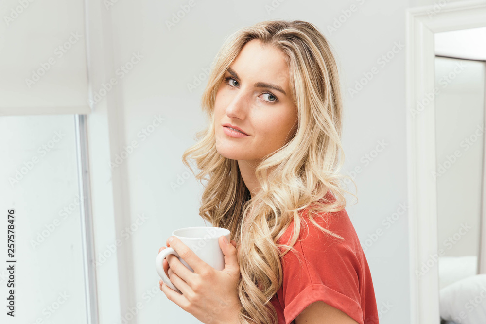Blonde drinking coffee, tea or soup from a white cup Blonde drinking coffee, tea or soup from a white cup