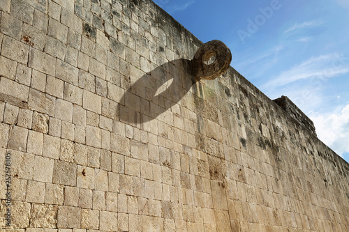 Chichen Itza - the wall of the Great Ball Court, high walls are rings carved by intertwined feathered snakes, beautiful blue sky. photo