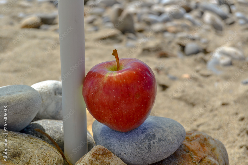 red apple on stones on sand background