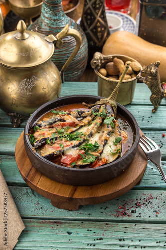 Baked eggplant stuffed with meat, tomatoes, paprika, onion and cheese on blue wooden table photo