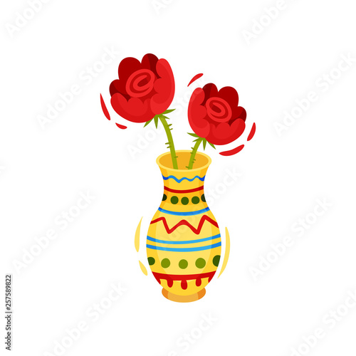 Red flowers in colorful vase on white background.