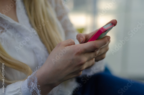 Close up image of young blond woman using her mobile phone background.