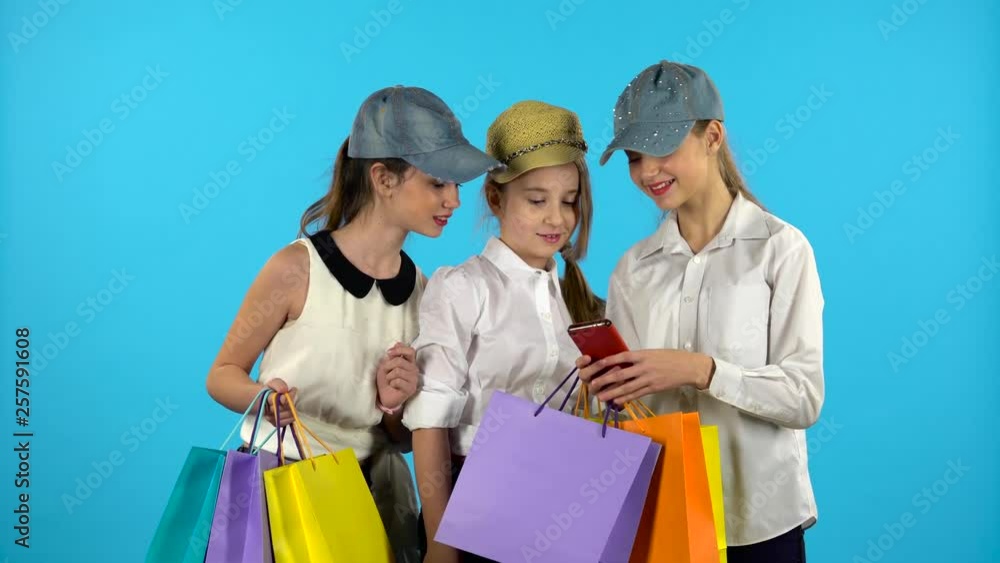 Three teenagers make selfies with colorful packages. Blue background Three teenagers make selfies with colorful packages. Blue background