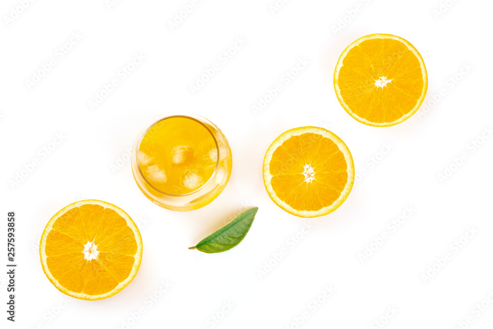 An overhead photo of a glass of fresh orange juice with orange halves and a green leaf on a white background with copy space