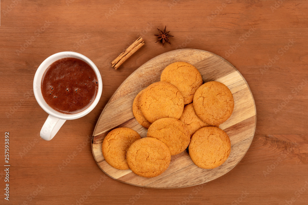 Ginger cookies with a mug of hot chocolate, a cinnamon stick, and an anise star, shot from above on a dark rustic wooden background with copy space Ginger cookies with a mug of hot chocolate, a cinnamon stick, and an anise star, shot from above on a dark rustic wooden background with copy space