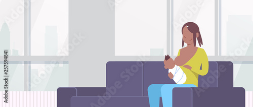 african american mother breastfeeding her newborn baby son woman sitting on couch motherhood nutrition lactation concept living room interior flat portrait horizontal