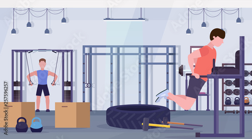 sports men doing exercises on parallel bar training apparatus guys working out in gym crossfit training healthy lifestyle concept modern health club studio interior