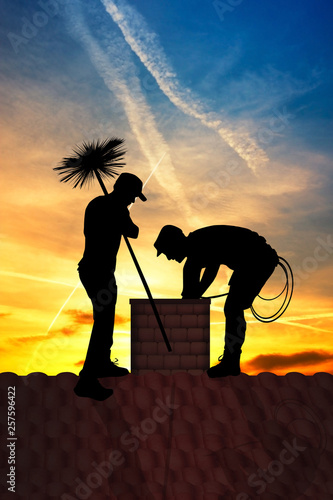 chimney sweep on the roof at sunset photo