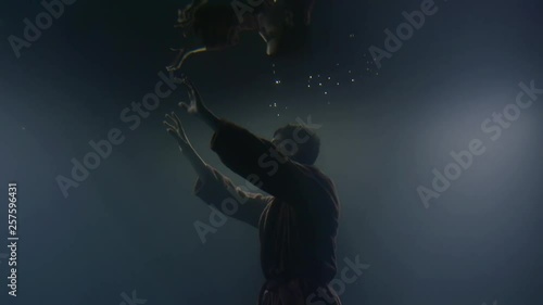Concept. Lonely drowning man floating underwater in dakrness, photo