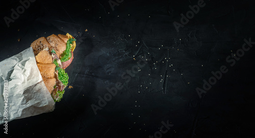 Fresh croissants sandwiches with lettuce, fried egg and prosciutto on dark background. Delicious and healthy breakfast