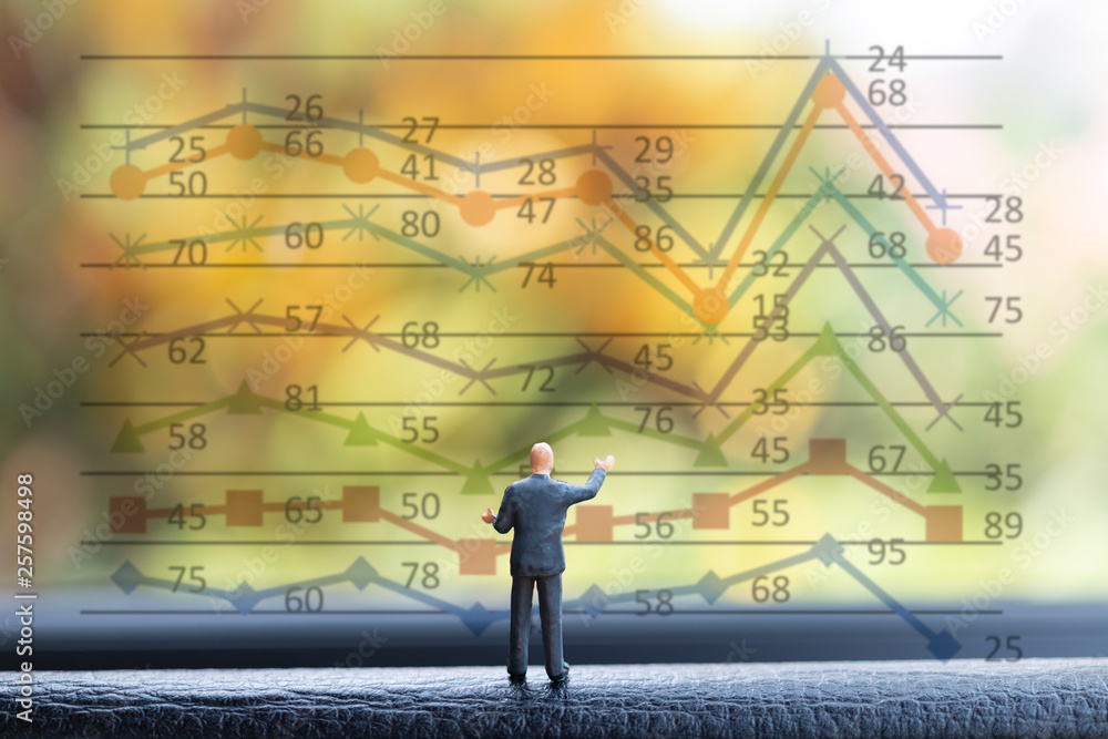 Miniature people businessman standing on front business of graph chart background Miniature people businessman standing on front business of graph chart background