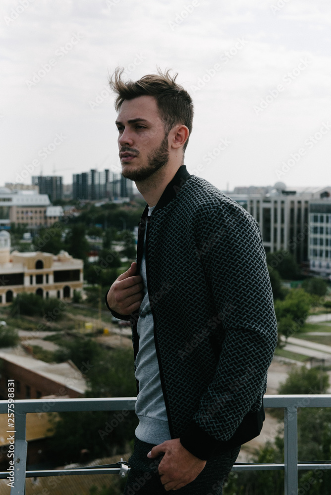 Fototapeta premium A man in a gray jumper with a zipper posing. Advertising of men's clothing.
