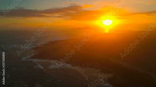 DRONE: Flying above the black rocky shoreline of a remote island at sunrise. © helivideo