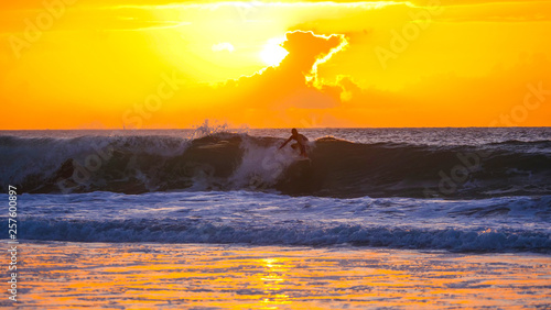 Pro male rider surfing cool ocean waves to remote beach in the early morning © helivideo