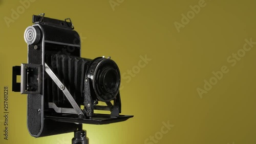 Vintage camera rotating against a yellow background photo