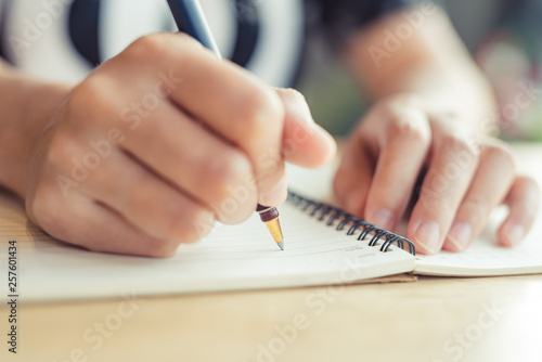 female hands with pen writing on notebook - Image