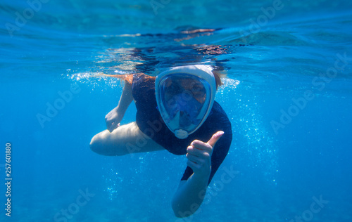 Woman snorkeling undersea portrait. Snorkel shows thumb up underwater. Happy woman snorkeling in blue water