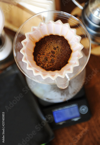 Coffee blooming in pink ceramic origami dripper. Top view. Alternative manual hand brewing photo