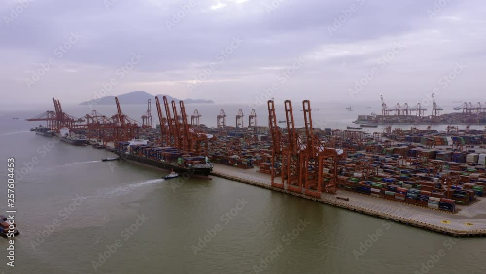 Drone shoot of landscape in Shenzhen,China.Cargo terminal full of containers,many cranes in the dock.Barges parked on smooth sea surface under cloudy sky. Drone shoot of landscape in Shenzhen,China.Cargo terminal full of containers,many cranes in the dock.Barges parked on smooth sea surface under cloudy sky.