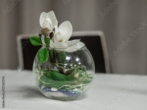 A bouquet of white orchids in a glass vase is on the table