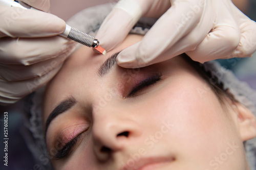 Permanent Makeup For Eyebrows. Microblading brow. Beautician Doing Eyebrow Tattooing For Female Face. Beautiful young girl in a beauty salon photo