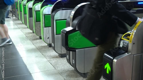 Anonymous Commuters Passing Through Ticket Gate At Subway Station