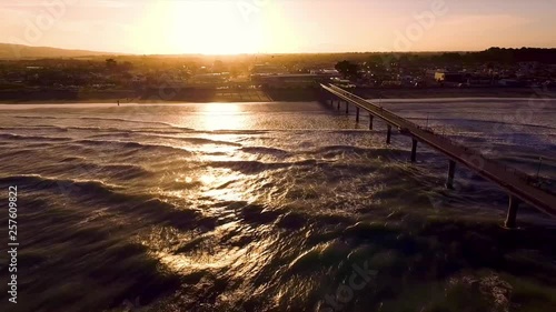 Aerial footage of pier in New Brighton, Christchurch, New Zealand during sunset with curious seagull flying towards the camera.