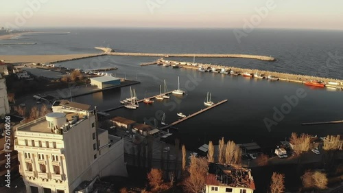 Pan aerial shot of Old Town Constanta City and harbor, Romania, Europe. Shot in spring during sunset and Golden Hour, revealing architecture, boats and coastline,  while seagulls fly photo