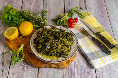 Φωτογραφία A dish of rare boiled grass stamnagathi (Cichorium spinosum) on a wooden backg