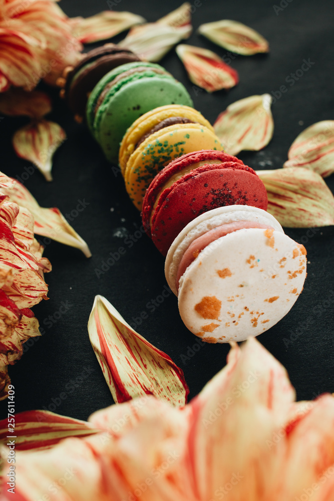 Composition of delicious bright macaroons and floral petals, sweet dessert