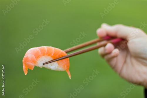Sushi ready to eat on chopsticks outdoors