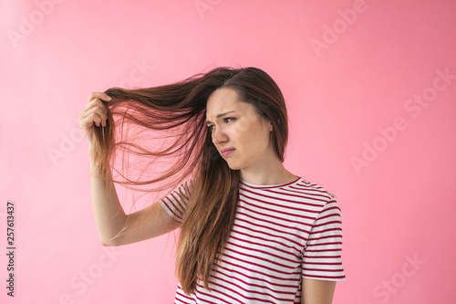 The girl is not happy with her hair and shows split ends or dandruff or dry hair or other problems.