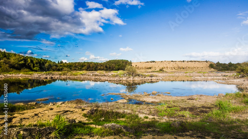 Sandy hills. Lake in the Sandy canyon. Warm colors background. Yellow sandstone textured mountain, white thin sand dune, bright sky. Sunshine landscape