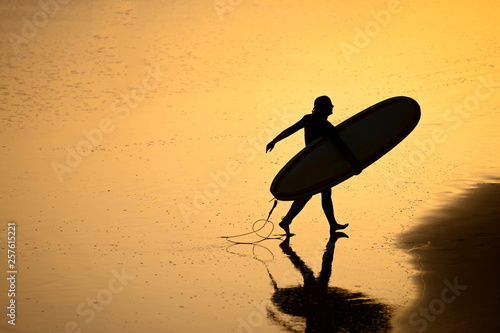 surfer goes to ride a board on the Moroccan coast of the Atlantic Ocean at sunset