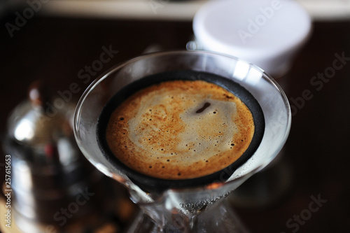 Alternative manual coffee brewing in black porous japonic ceramic paperless dripper filter. Glass jug. Closeup top view photo