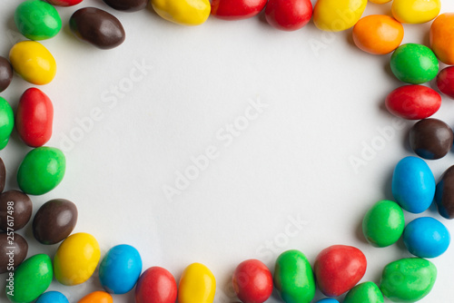 Colorful frame of multicolored candies on white background