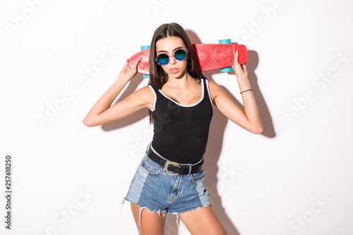 Portrait of a young smiling girl holding skateboard isolated on a white background.