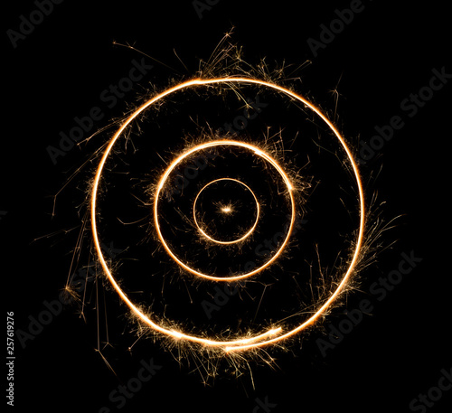 Sparkler concentric circles. Burning bengal fire concentrical round letter o number zero. Isolated on black.