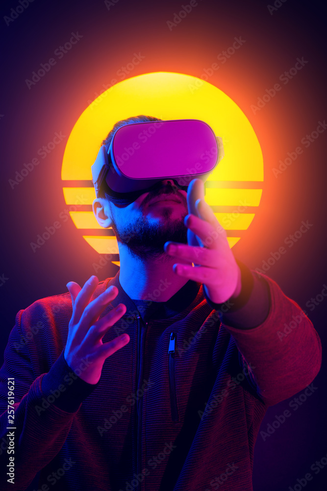 80's synth wave and vapor wave futuristic aesthetics. VR video game experience. Man wearing virtual goggles wireless headset and interacting gestures. foto de Stock | Adobe Stock