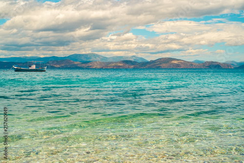 Wooden fishing boat floating in a beautiful clear emerald water. Peloponnese, Greece.