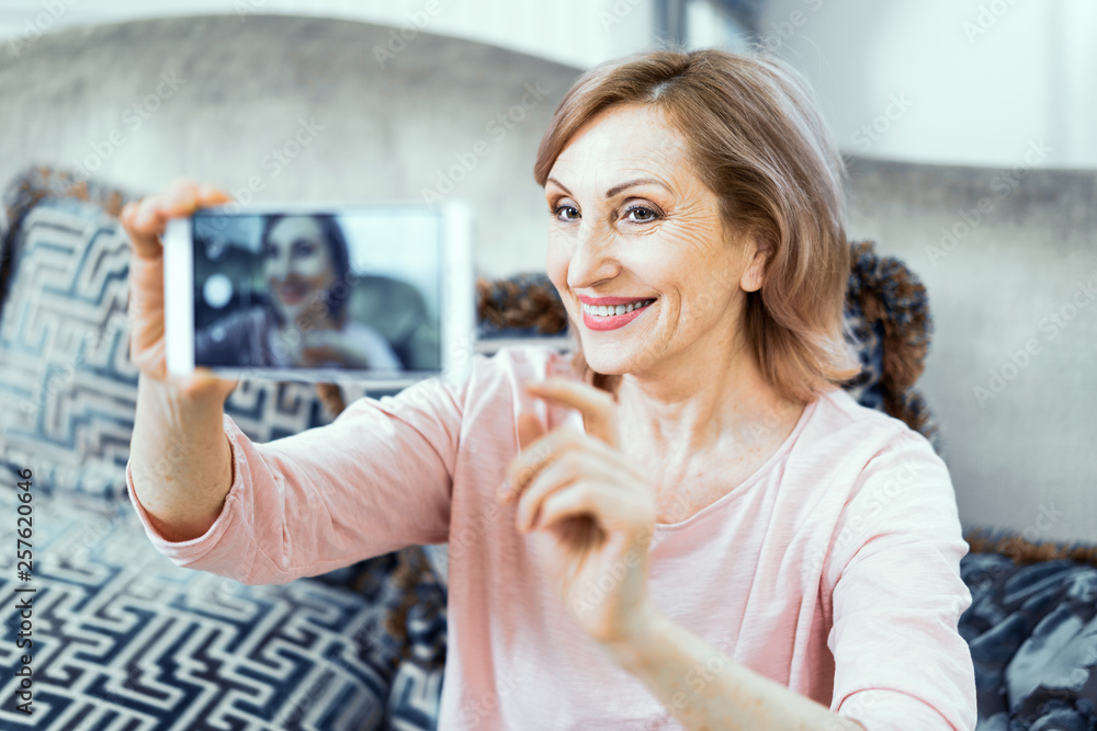 Elderly Woman With a Phone in Her Hands in Good Mood is Resting at Home in the Living Room.