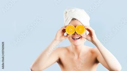Portrait of a cheerful feminine girl, with natural clear skin, a girl with orange slices, covering her eyes, The concept of skin care,