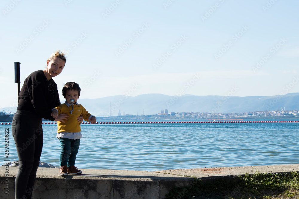  Baby walking on the wall with his mother on the beach