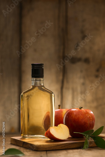 Bottle of fresh cider near autumn apples on dark wooden background