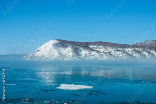 Ice floes floating in river in winter with background of snow mountain