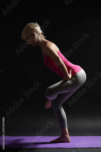 Woman exercising pilates. Standing glute and hamstring stretch.