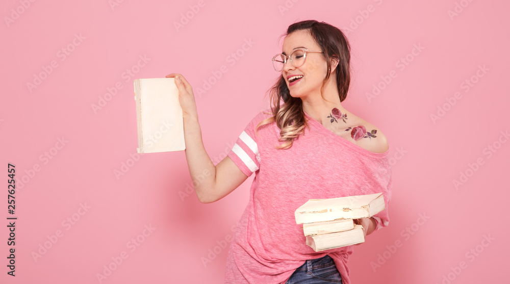 Portrait of a girl with a stack of books on a pink background Portrait of a girl with a stack of books on a pink background